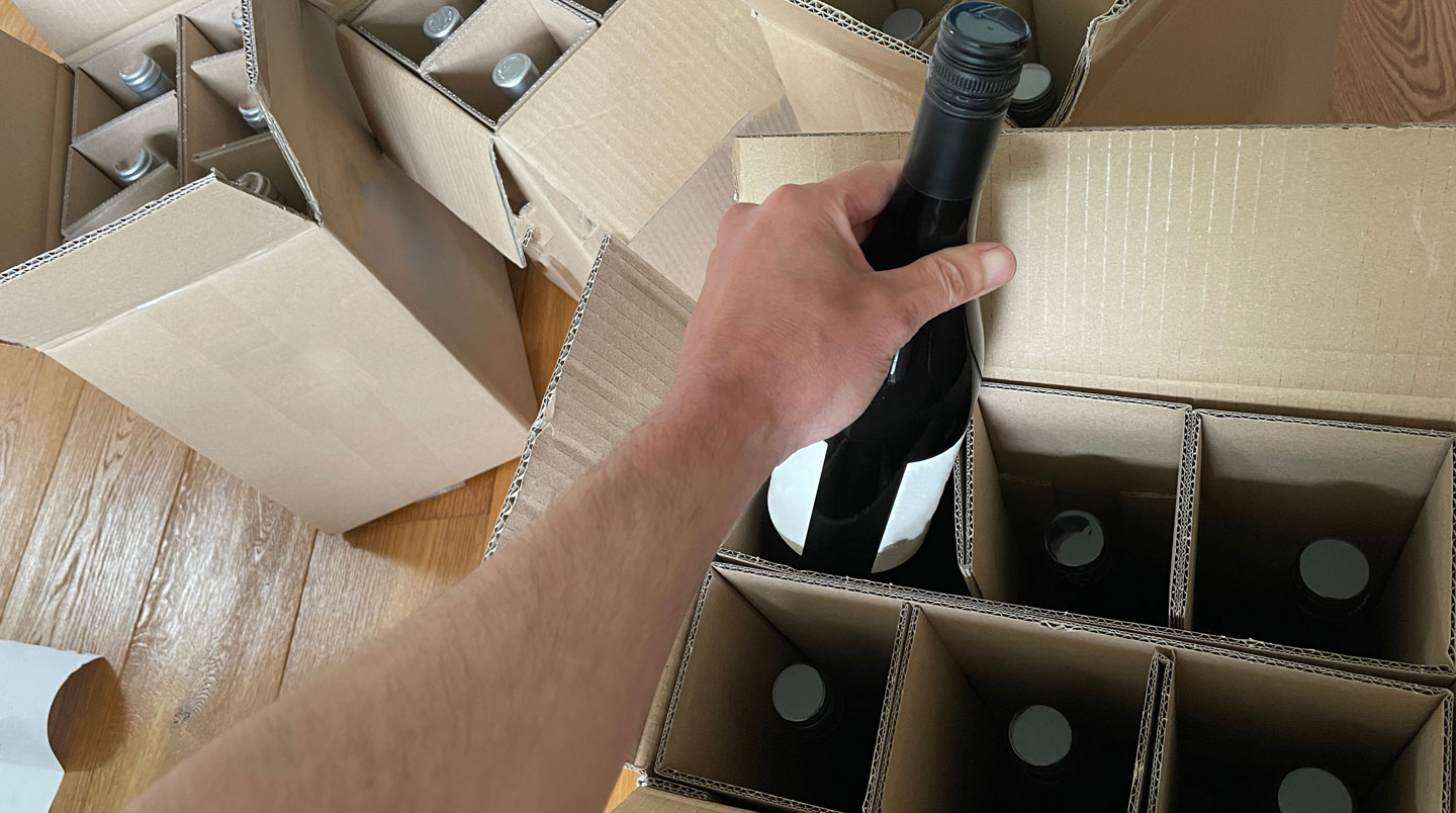 Colis ouvert montrant des bouteilles de vin protégées par emballage sécurisé en carton